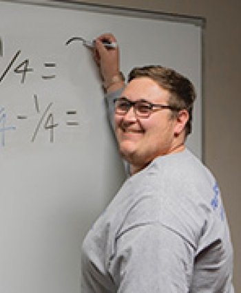 91Ӱ Transfer Student Zach Little stands at a whiteboard teaching math.