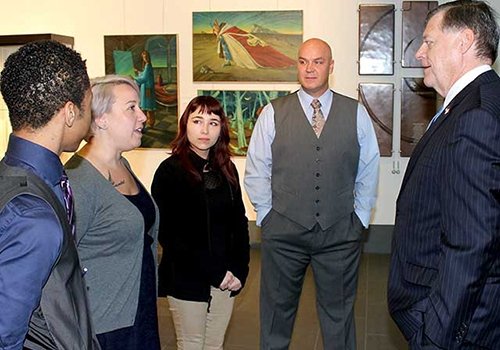 91Ӱ TRIO students visit with a congressman at an art gallery.