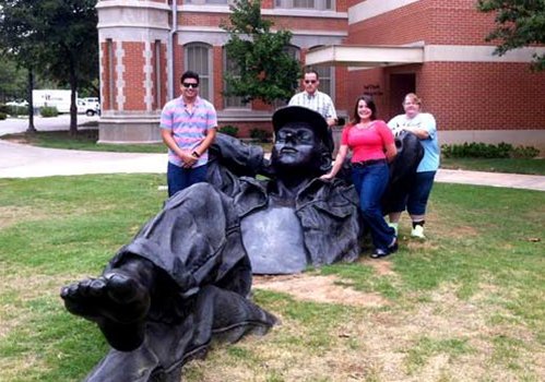Four 91Ӱ TRIO Students stand behind a large stature of a reclining man.